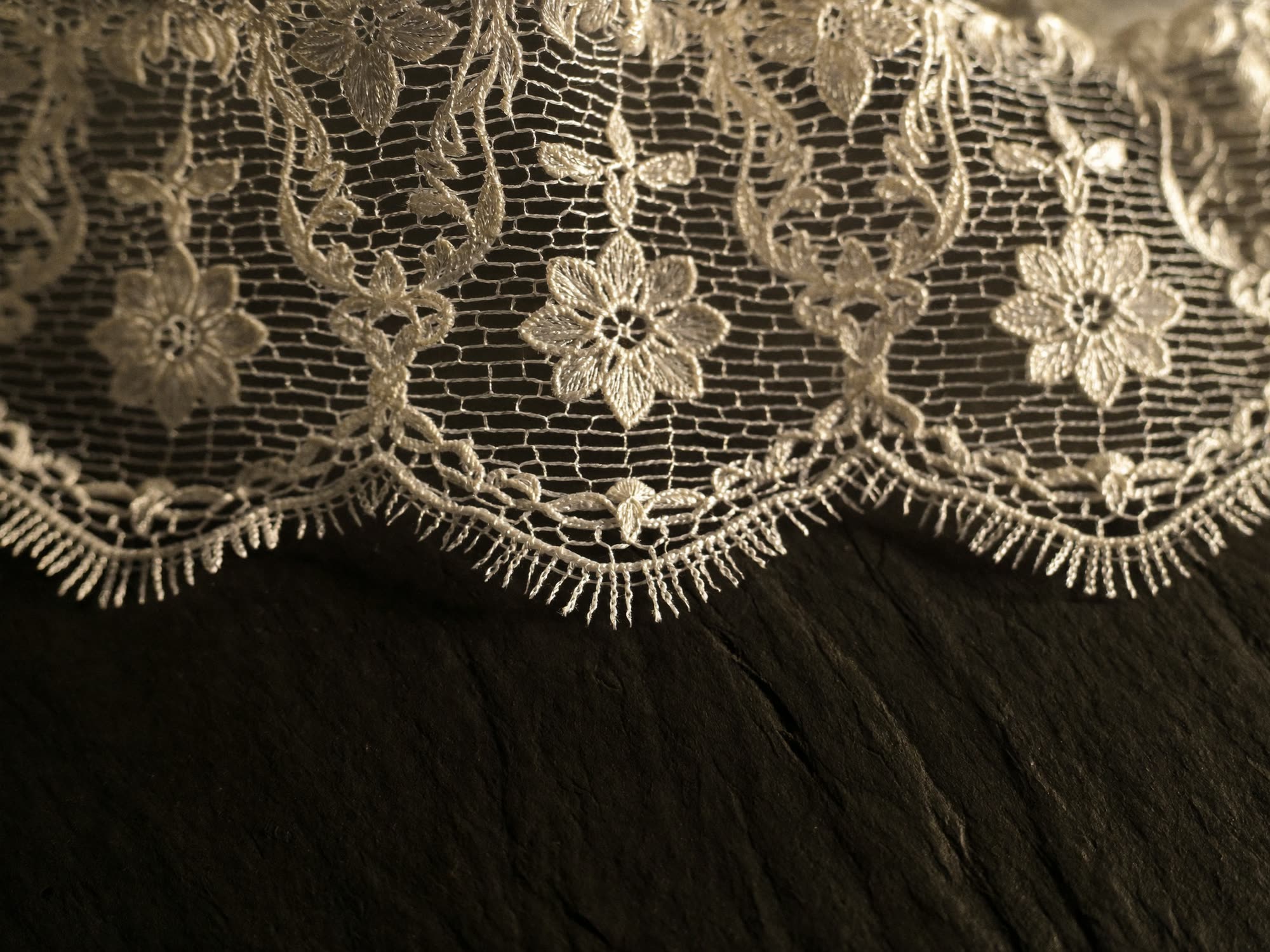 Macro of fine ivory bridal lace on a dark surface
